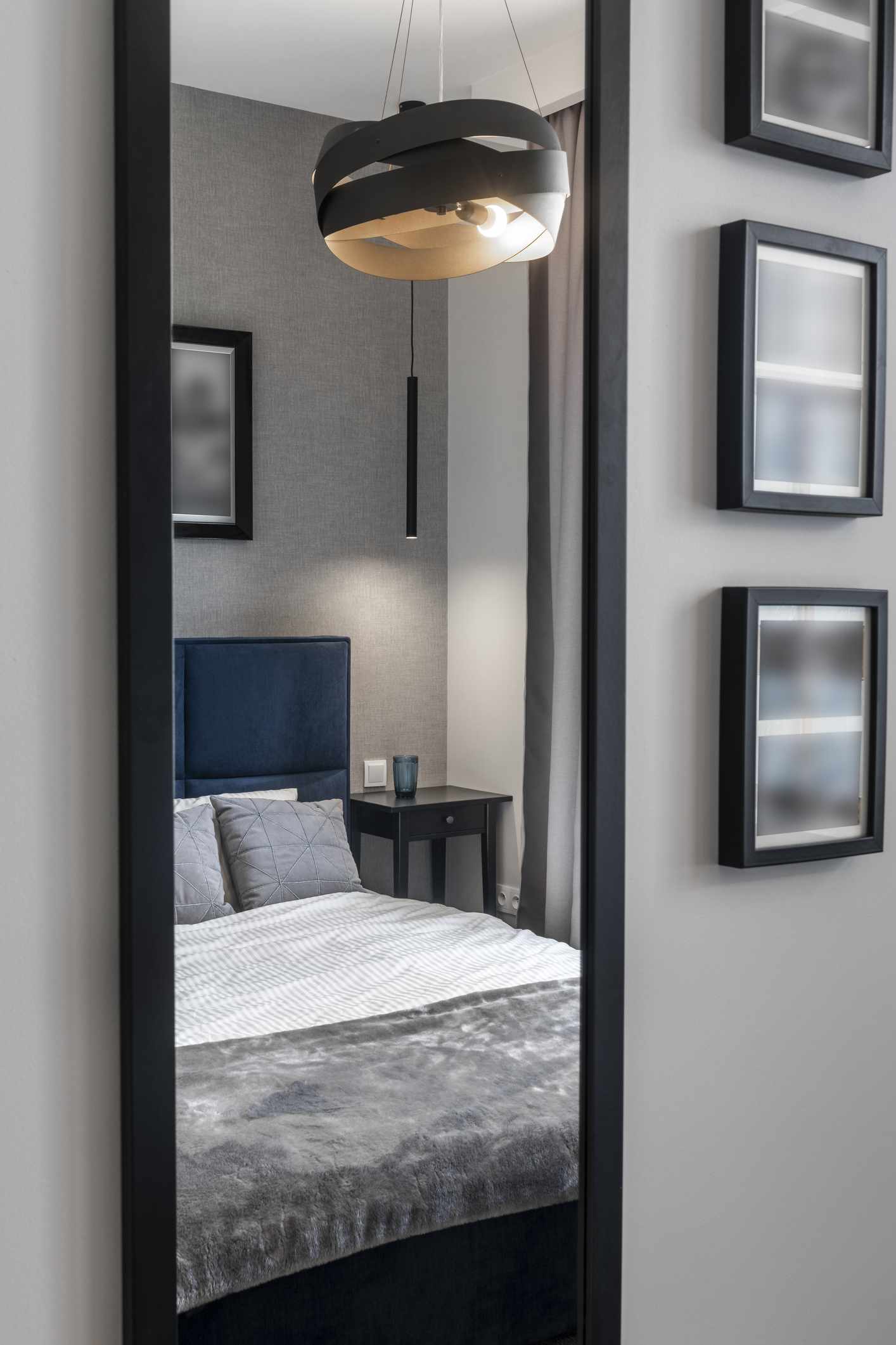 Chambre à coucher moderne en finition grise avec lit bleu et miroir face au lit