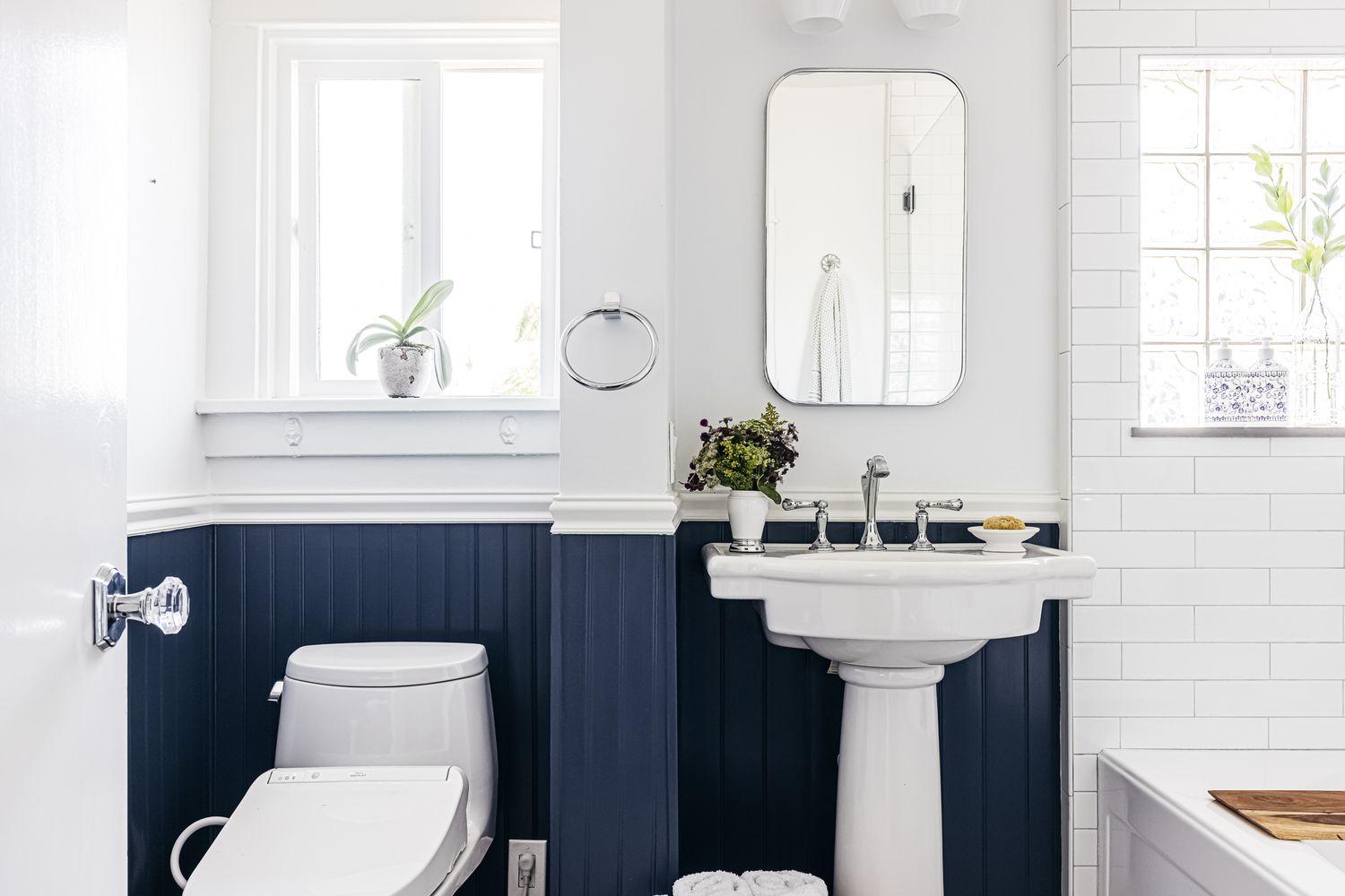 Petite salle de bain aux murs blancs divisés par un traitement en lambris bleu marine