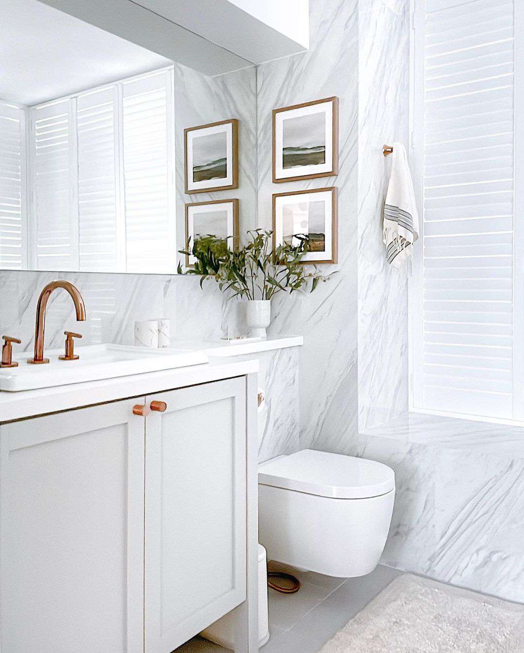 Salle de bains blanche et lumineuse avec fenêtre à volets intégrée pour plus d'intimité.