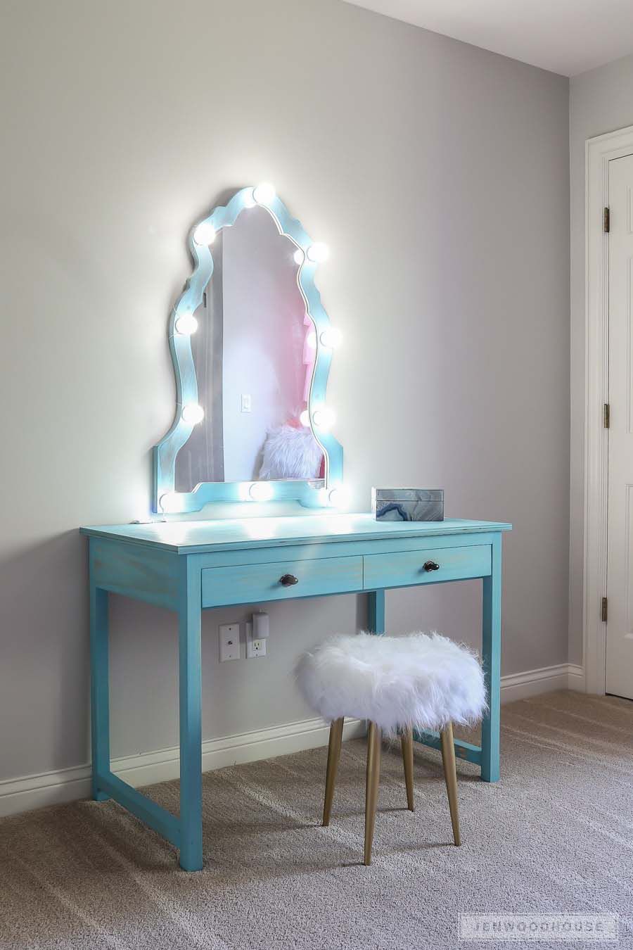 Un meuble-lavabo bleu avec un miroir éclairé