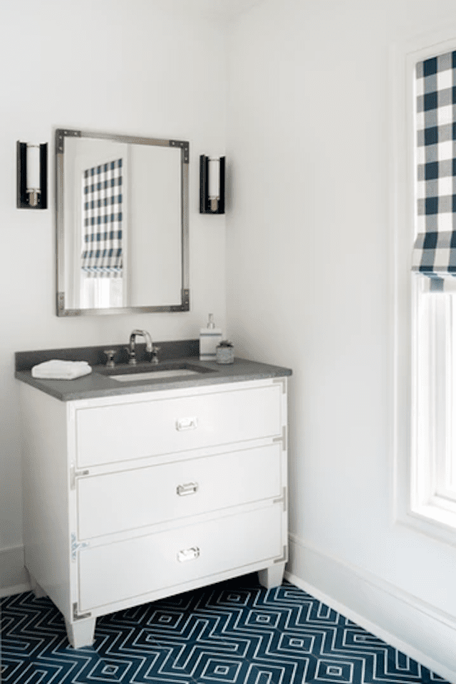 Meuble-lavabo blanc avec miroir chromé et deux appliques au-dessus.