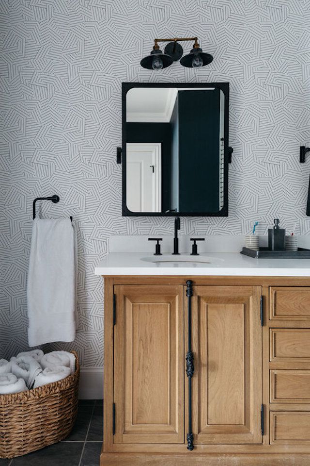 Salle de bain avec meuble-lavabo en bois, accessoires noirs et papier peint noir et blanc