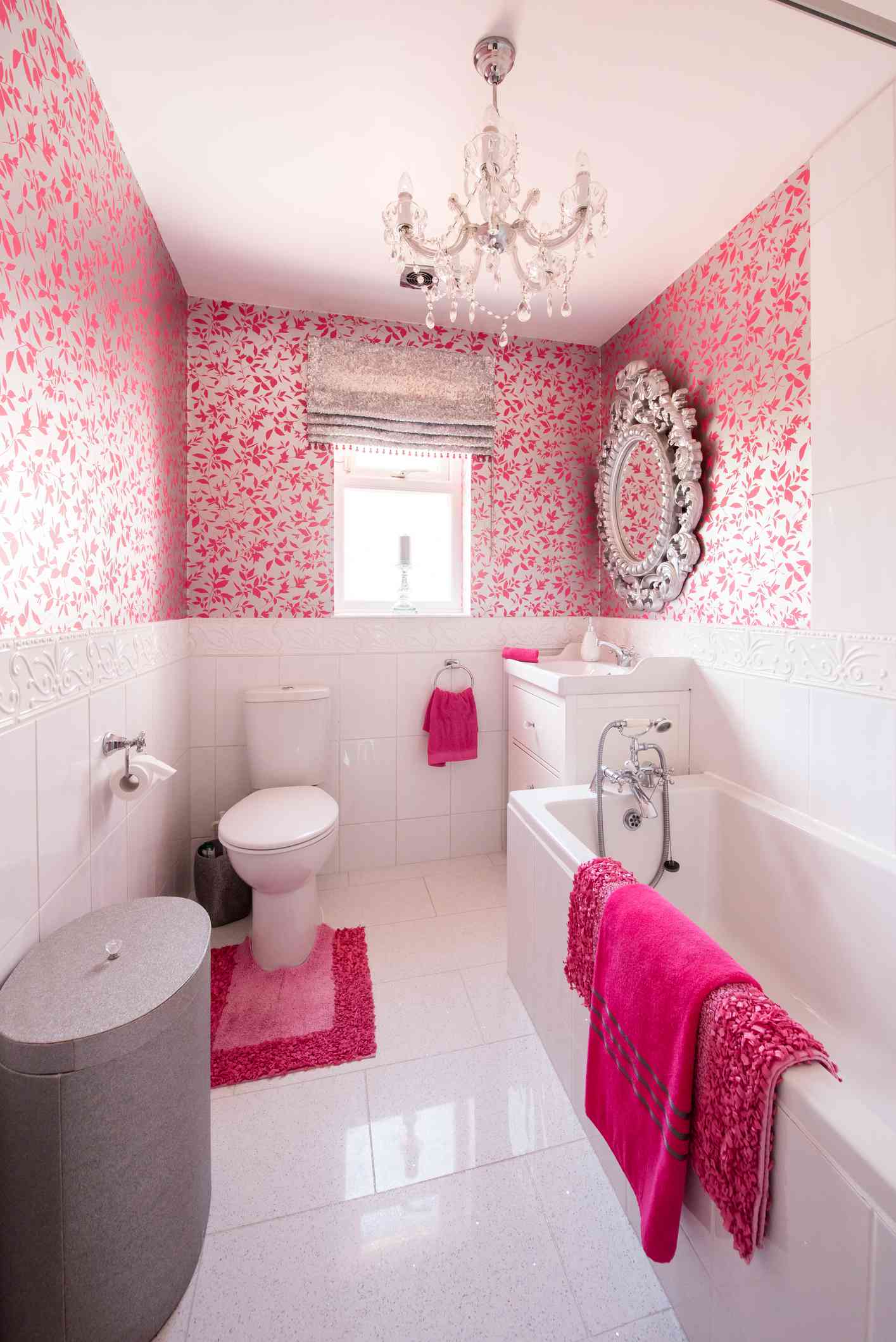 Salle de bains rose avec lustre et miroir orné
