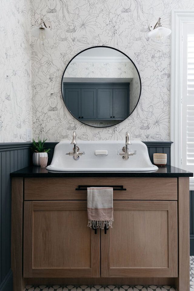Meuble de toilette en bois avec miroir rond au-dessus et papier peint floral
