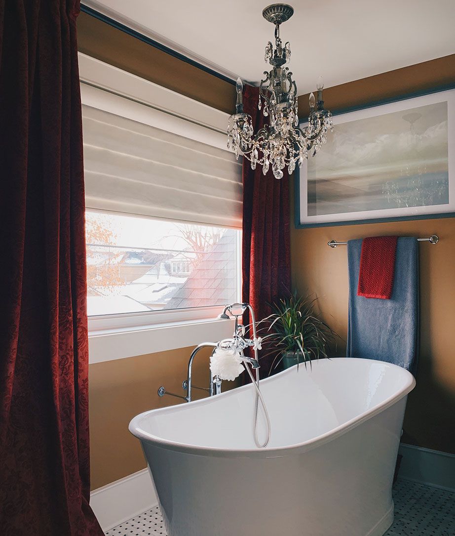 Une baignoire avec des rideaux de velours rouge et un petit lustre en cristal.