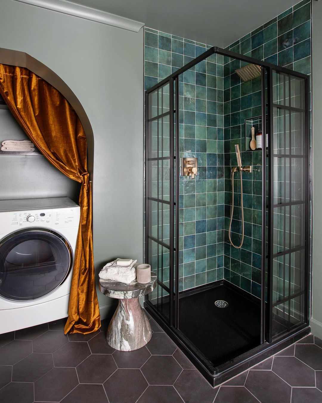 Rideau de velours doré dissimulant un lave-linge et un sèche-linge dans une salle de bains.