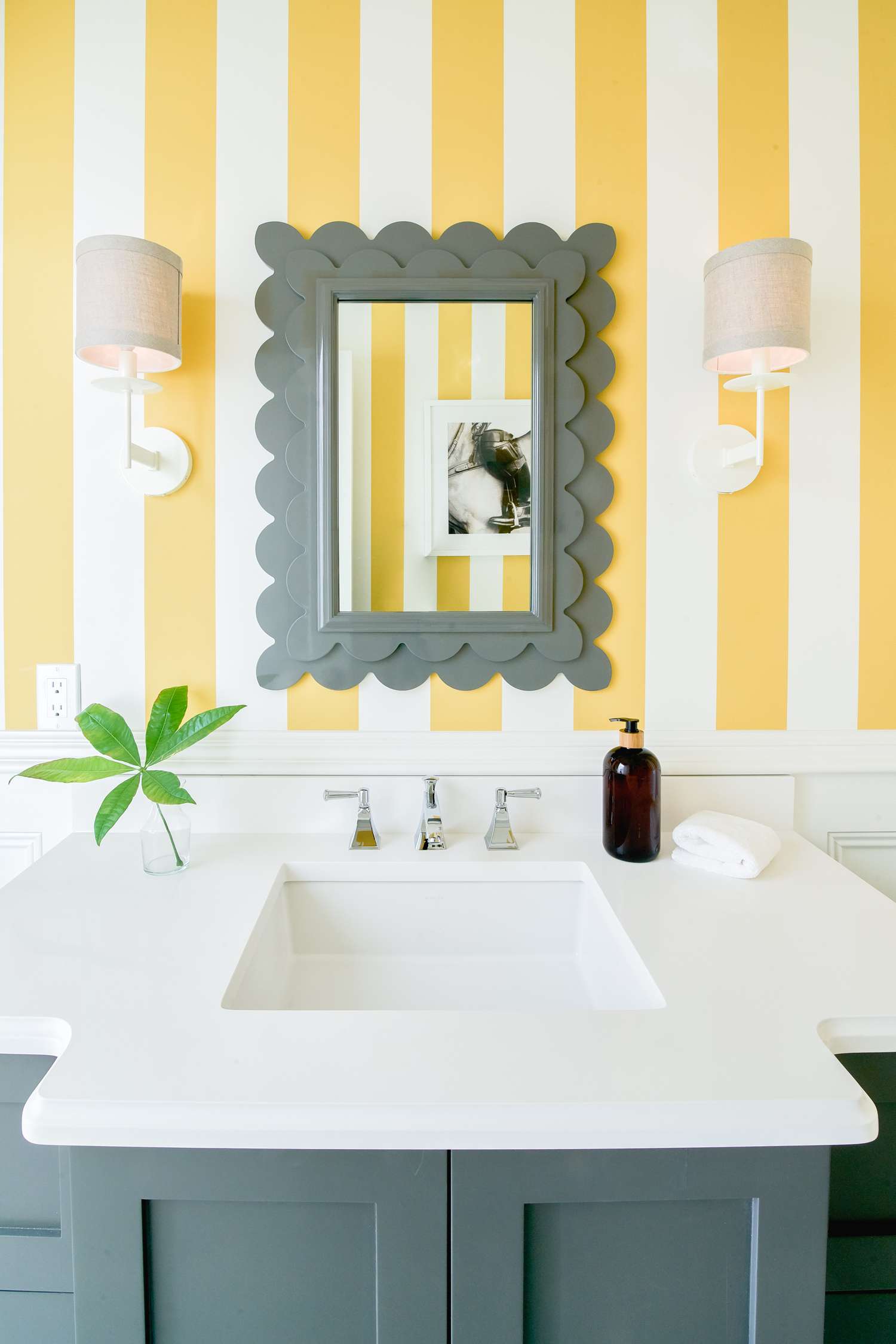 Miroir gris festonné contre un mur rayé dans une salle de bain