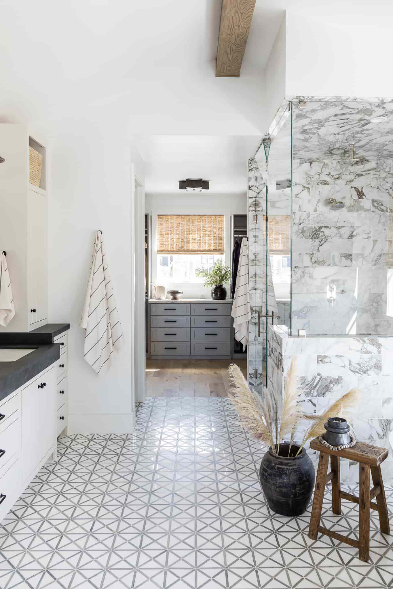 Une salle de bain avec une douche en marbre et un décor d'herbe de la pampa