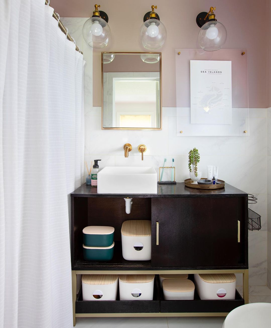 Des bacs de rangement élégants dans une salle de bain rose et blanche