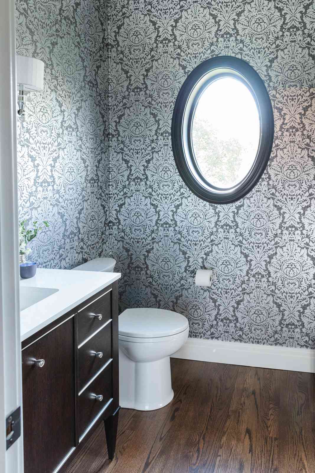 Une petite salle de bains avec du papier peint damassé