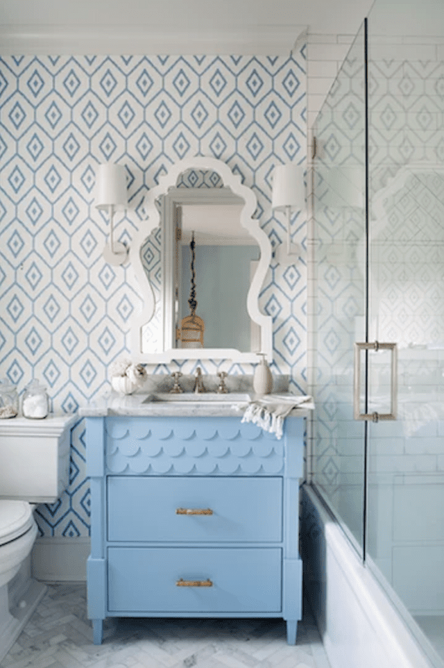 Meuble-lavabo bleu avec miroir blanc au-dessus sur un mur tapissé de bleu et de blanc