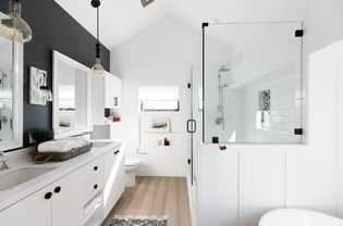 Belle salle de bain avec armoires blanches et accents muraux noirs 