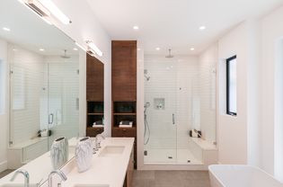Salle de bains moderne avec armoire en bois entourée de murs et comptoirs blancs