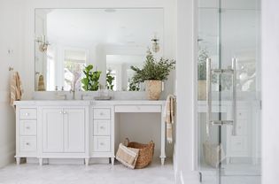 Une salle de bain entièrement blanche, à part quelques accents beiges et quelques plantes vertes